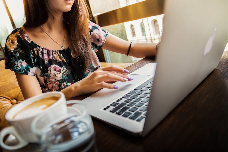 chica trabajando con portátil y tomando un café